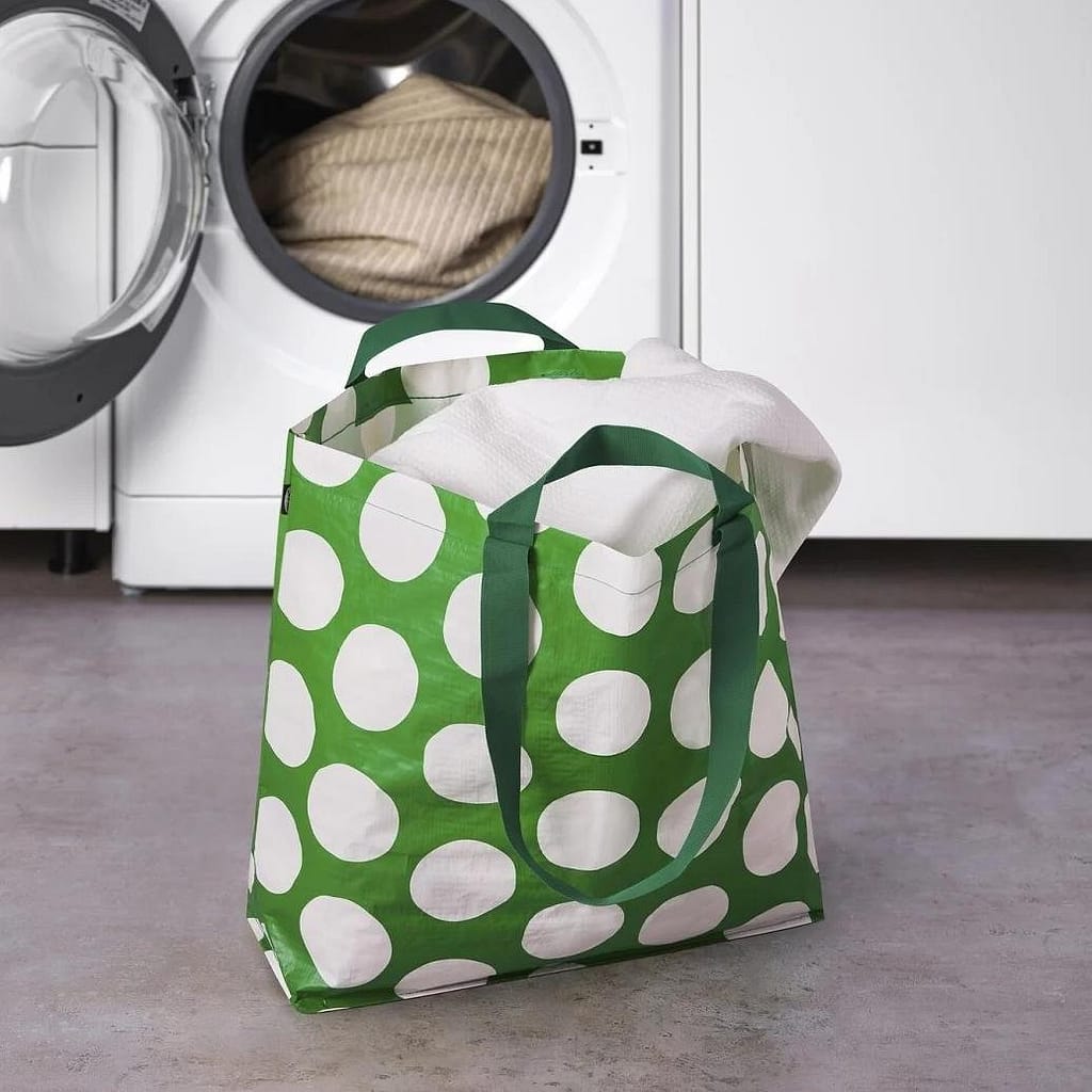 A tote bag made of non-woven polypropylene is placed in front of the washing machine