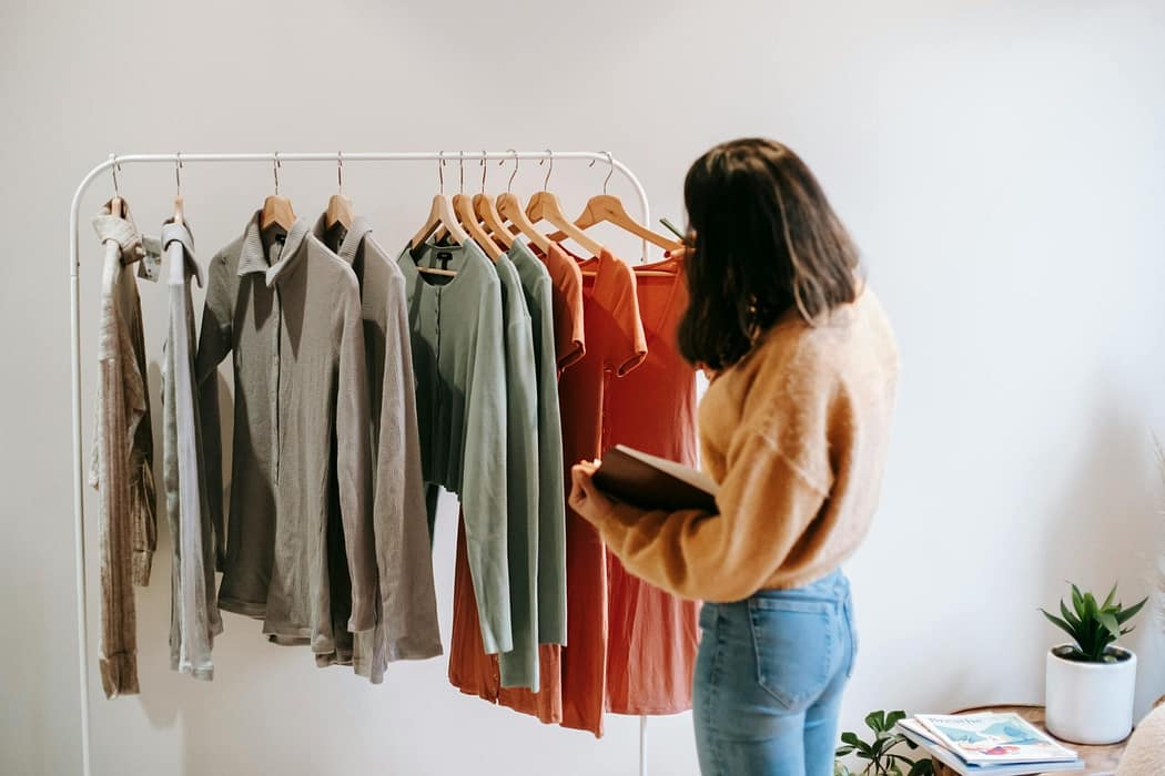 A woman is examining the garments that have been produced and she needs to develop a business plan for the clothing line
