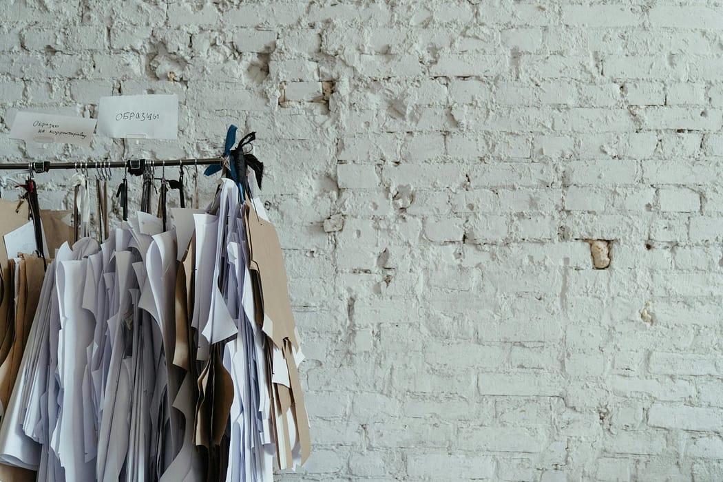 Clothing patterns hanging on a rail against a white brick wall