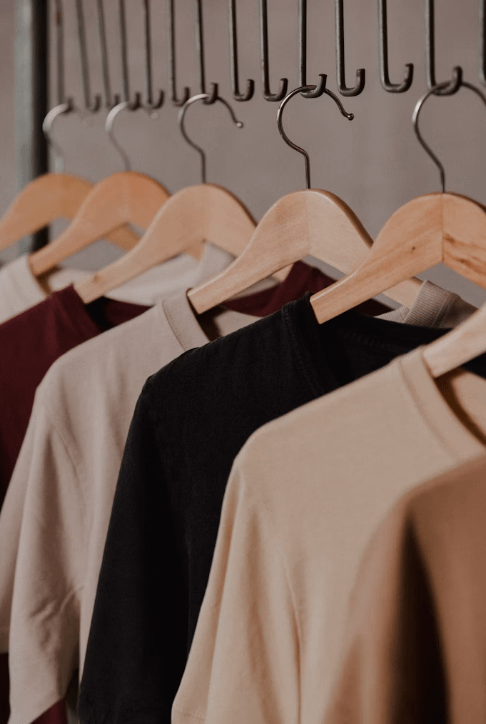 There are several hoodies hanging on the clothes rack.