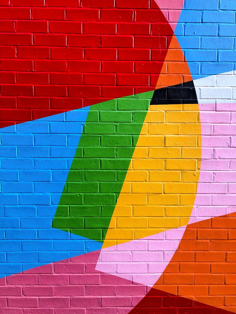 A colorful brick wall presents a rich color combination, echoing aspects like color interactions and the color wheel in color theory. It visually demonstrates elements such as hue, saturation involved in color theory.