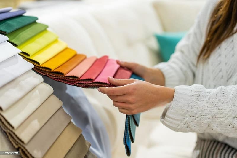 A woman is picking out the lightest fabric for the hot weather