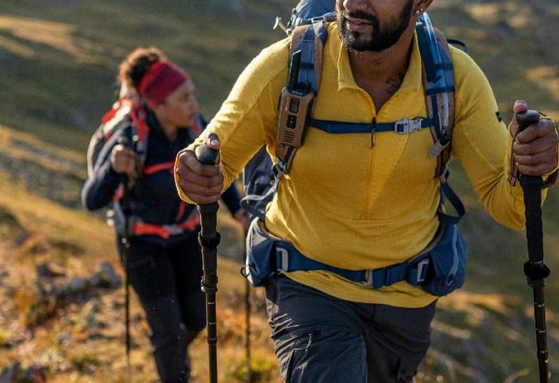 A man and a woman dressed in professional outdoor wear are climbing a mountain.