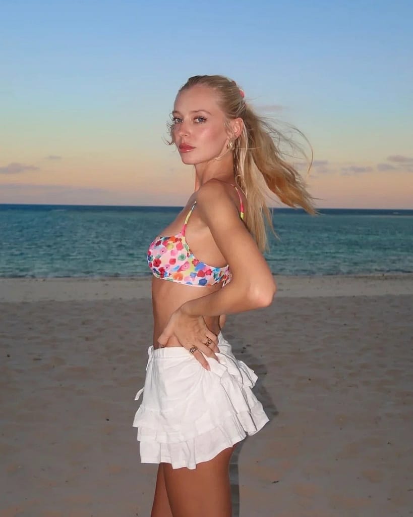 A woman standing by the beach in a split bathing suit.
