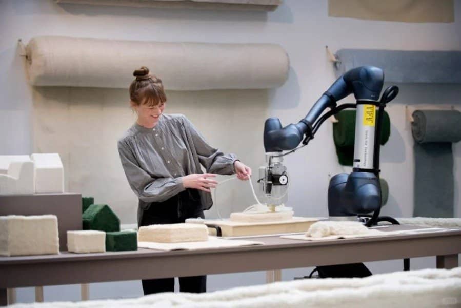 The woman in this photo is using a 3D knitting technology machine to create her work.