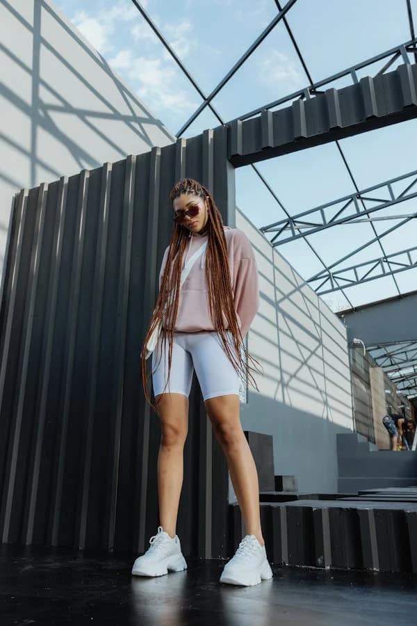 A vibrant lady wearing a cropped hoodie and tight shorts, with a crossbody bag to enhance her fashion sense