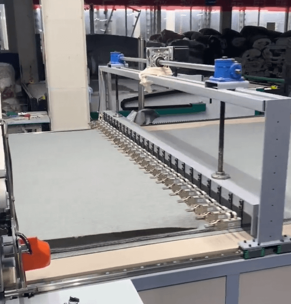 This is a picture of an automatic spreading machine laying down layers of fabric in a precise and even manner.