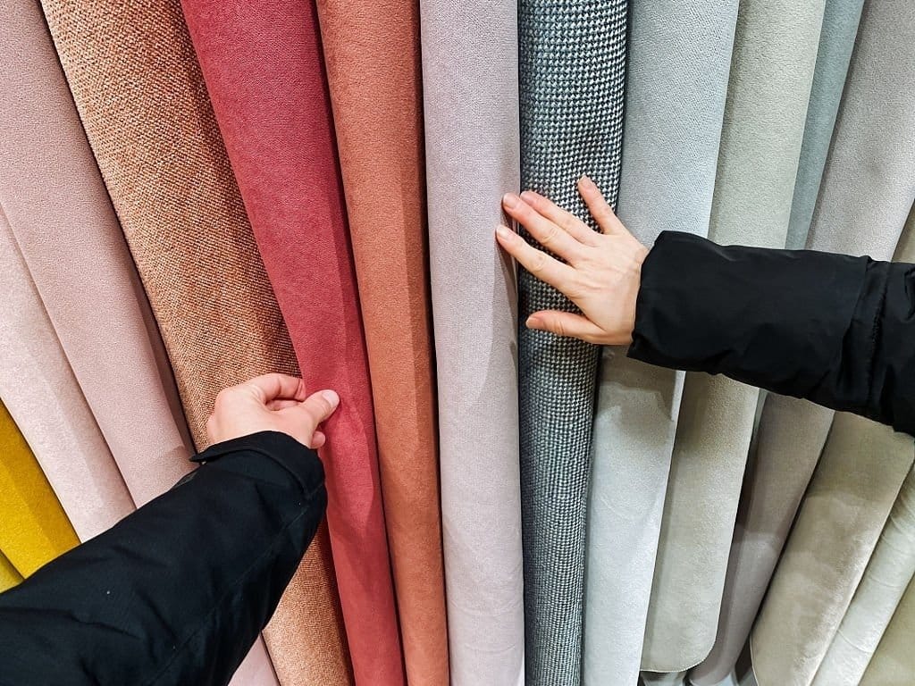 A person is gently touching beautiful fabric while browsing various textiles in a store, Fully experiencing the fabric handfeel